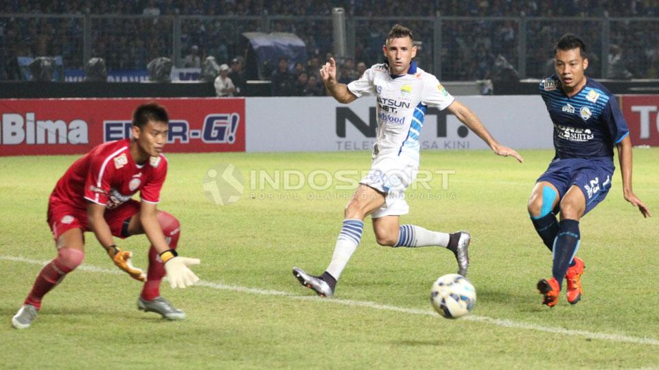 Kiper Arema Kurnia Meiga (kiri) berhasil menghalau laju bola dari serangan Persib Bandung.